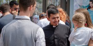 web3-catholic-priest-roman-collar-public-bus-station-people-talking-shutterstock